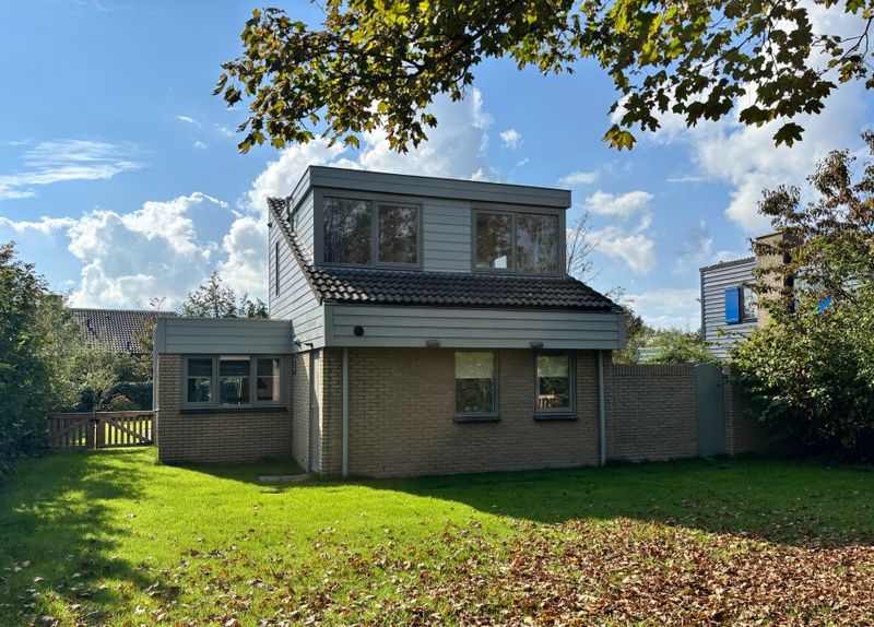 Vacation home B 011 in De Cocksdorp, Texel, surrounded by green nature and blue skies, ideal for a relaxing stay on the Wadden Islands.