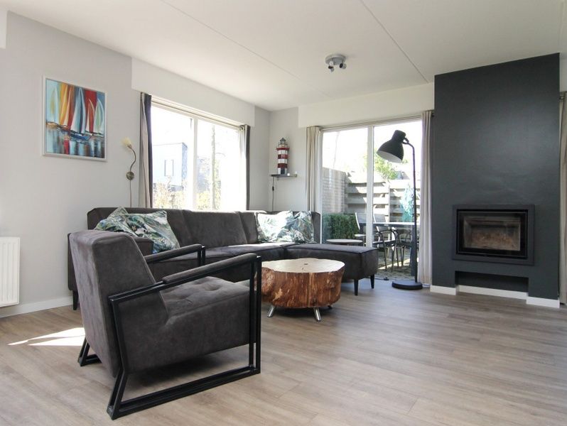 Cozy living room in Holiday Home B 011, De Cocksdorp, Texel, with modern furnishings and views of the Wadden Island garden.