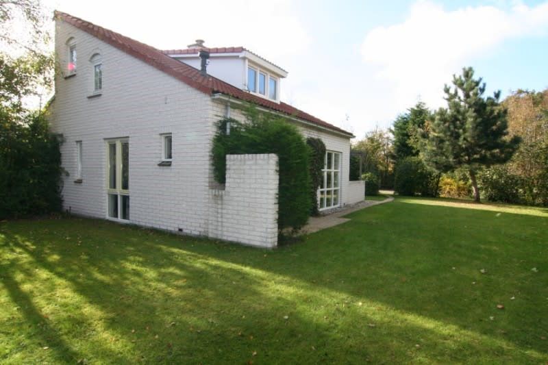 Das Ferienhaus D 760 in De Cocksdorp, Texel, bietet eine ruhige Gartenumgebung mit gruenem Rasen und Privatsphaere fuer einen entspannten Aufenthalt.