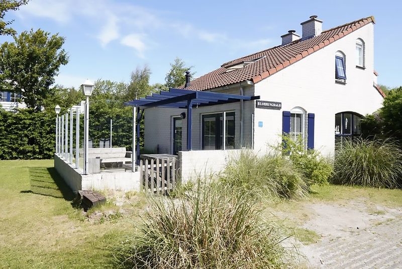 Vakantiehuis D 696 in De Cocksdorp, Texel met zonnige veranda en groene omgeving, ideaal voor een ontspannen verblijf op de Waddeneilanden.