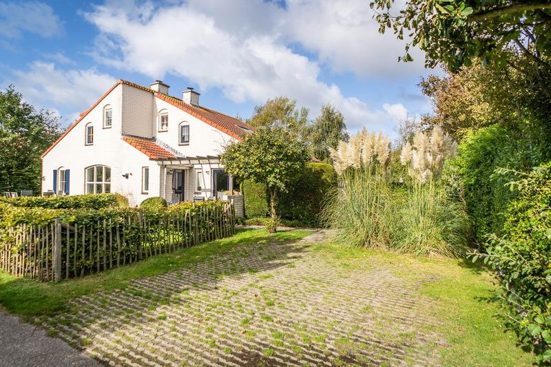 Vakantiehuis D 694 in De Cocksdorp, Texel, omgeven door weelderige natuur en een uitnodigende tuin met groen uitzicht.