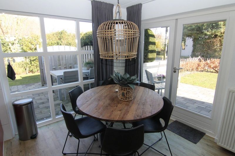 Gezellige eetruimte in Vakantiehuis D 694, De Cocksdorp, Texel met uitzicht op de tuin en terras, ideaal voor een ontspannen verblijf.