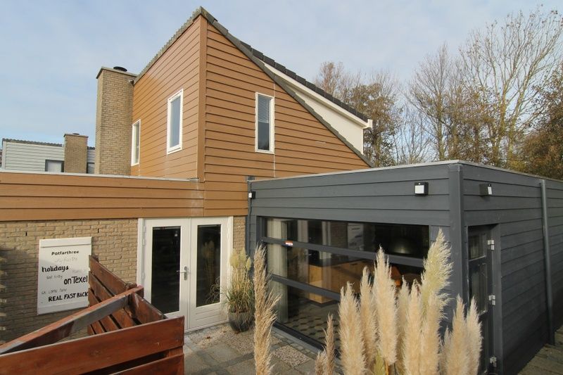 Vakantiehuis B 015 in De Cocksdorp op Texel, Waddeneilanden, met moderne architectuur en ruime veranda omgeven door natuurlijke schoonheid.