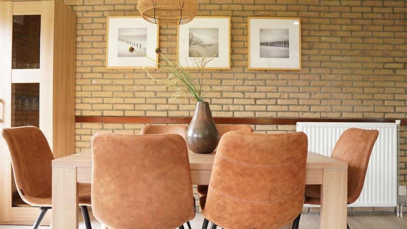 Gezellige eetkamer van Vakantiehuis B 031 in De Cocksdorp, Texel, met stijlvolle inrichting en kunst aan de muur voor een ontspannen verblijf.