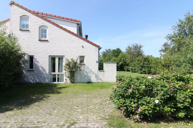 Vakantiehuis D 800 in De Cocksdorp, Texel, omgeven door groen en bloemen, ideaal voor een ontspannen verblijf op de Waddeneilanden.