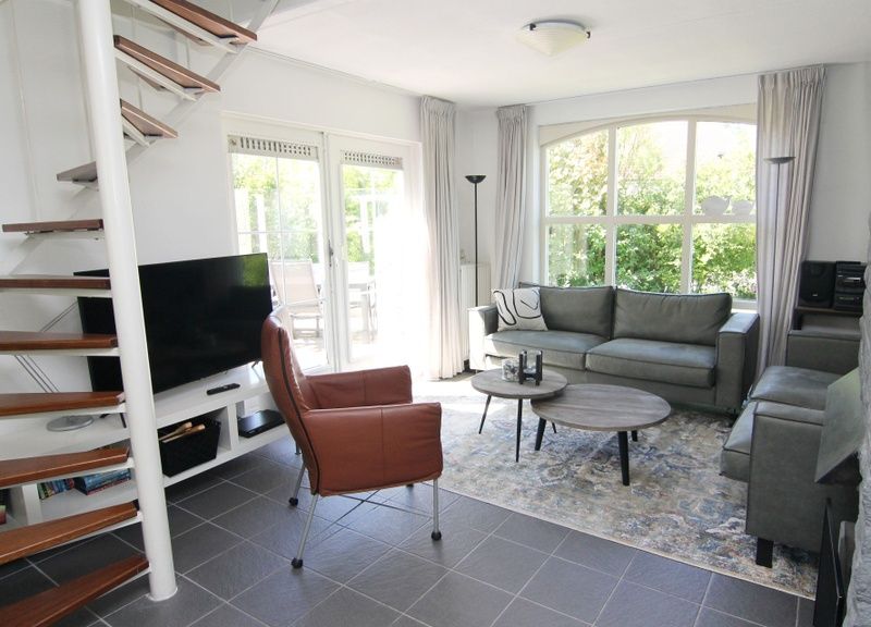 Gezellige woonkamer van Vakantiehuis E 724 in De Cocksdorp, Texel. Comfortabele zithoek met uitzicht op de groene tuin van de Waddeneilanden.