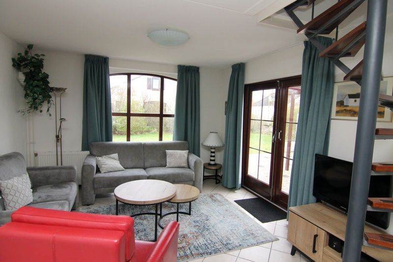 Gezellige woonkamer in Vakantiehuis E 655, De Cocksdorp, Texel. Comfortabele zithoek met uitzicht op de groene tuin van de Waddeneilanden.