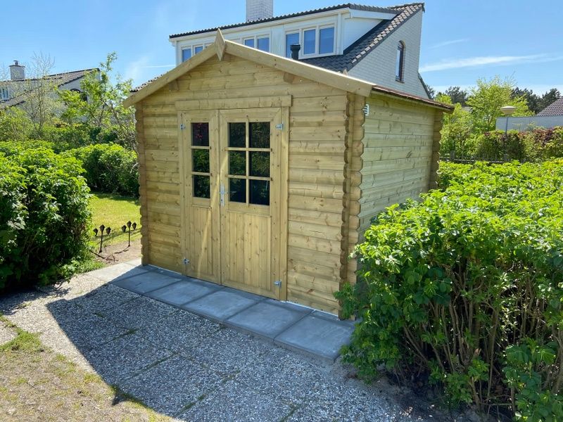 Gartenhaus aus Holz im Ferienhaus D 657 in De Cocksdorp, Texel, umgeben von gruener Natur auf den Watteninseln.