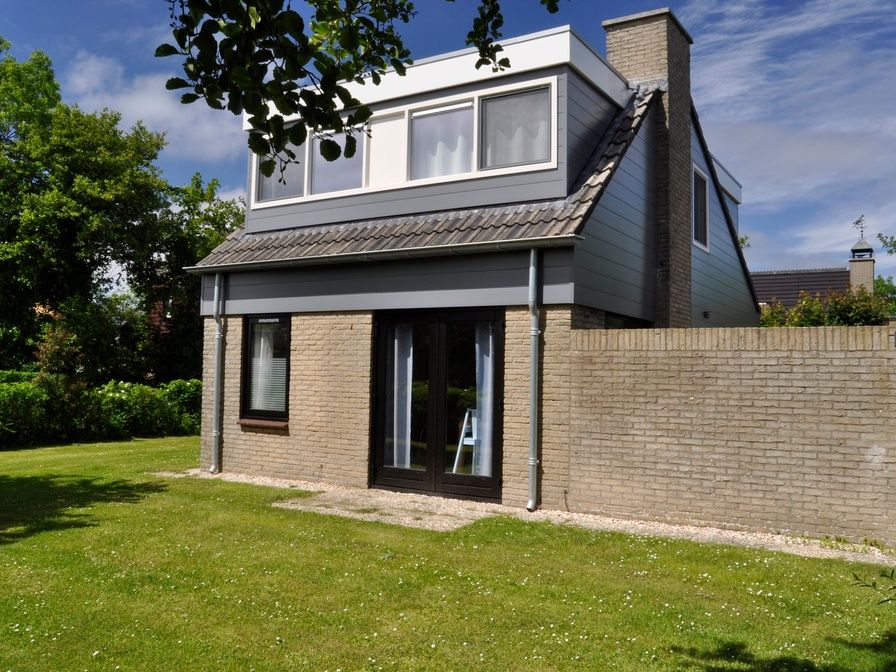 Das Ferienhaus B 043 in De Cocksdorp, Texel, bietet einen ruhigen Garten und eine moderne Architektur fuer einen erholsamen Aufenthalt auf den Watteninseln.