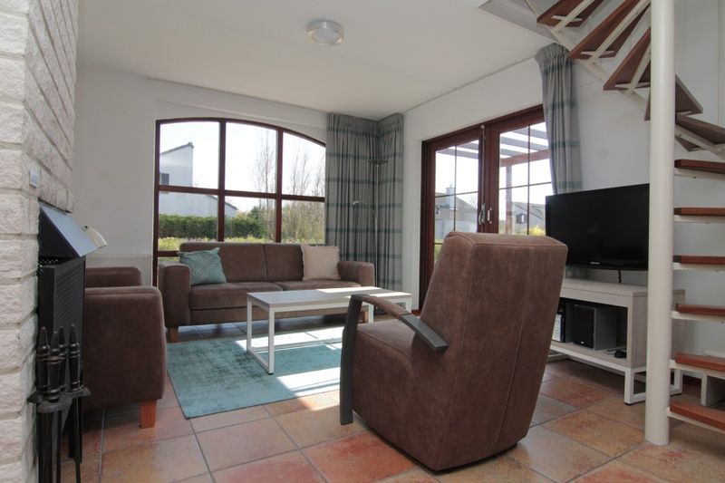 Cozy living room in Holiday home E 645, De Cocksdorp, Texel. Comfortable interior with spacious seating area and views of the green surroundings.