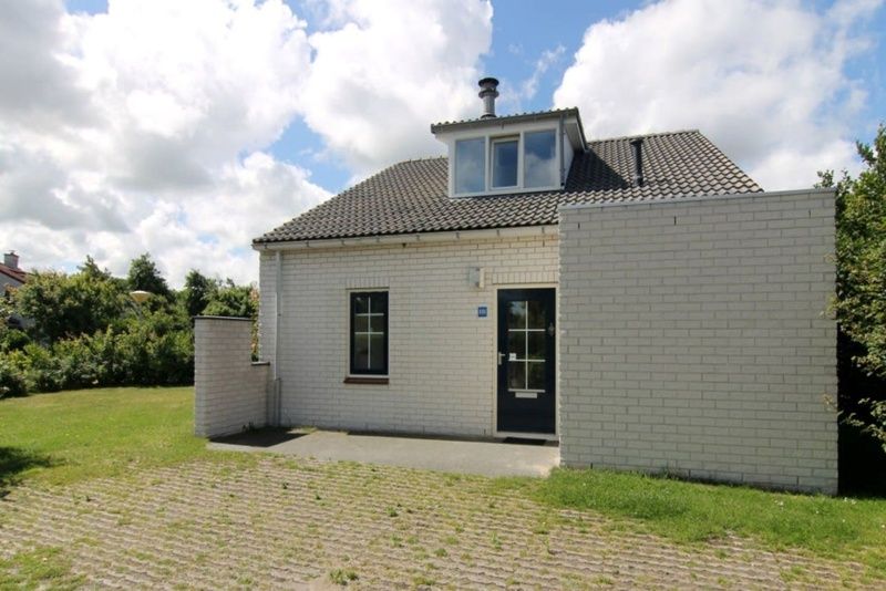 Vakantiehuis F 808 in De Cocksdorp, Texel, omgeven door groene natuur en een zonnige veranda, ideaal voor een ontspannen verblijf op de Waddeneilanden.