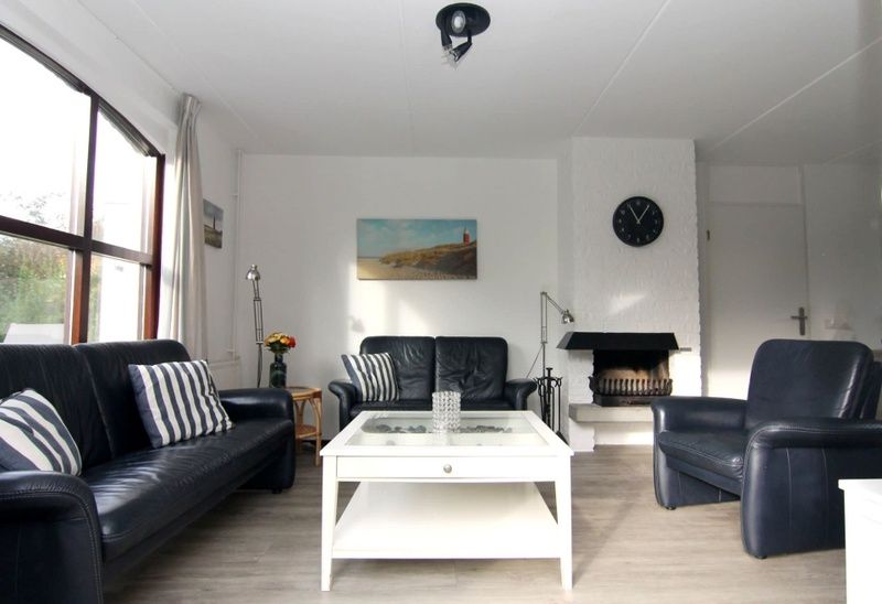 Gezellige woonkamer in Vakantiehuis F 575, De Cocksdorp, Texel, met comfortabele zithoek en open haard voor een ontspannen verblijf.