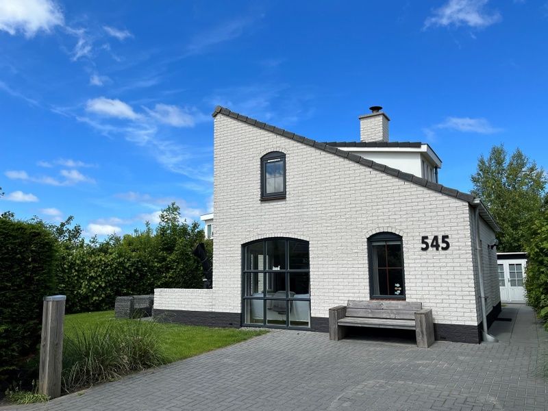 Vakantiehuis E 545 in De Cocksdorp, Texel, met charmante witte gevel en groene omgeving, ideaal voor een ontspannen verblijf op de Waddeneilanden.