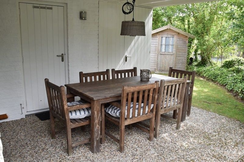 Geniet van de rust op de overdekte veranda van Vakantiehuis F 455 in De Cocksdorp, Texel, met uitzicht op de groene omgeving.