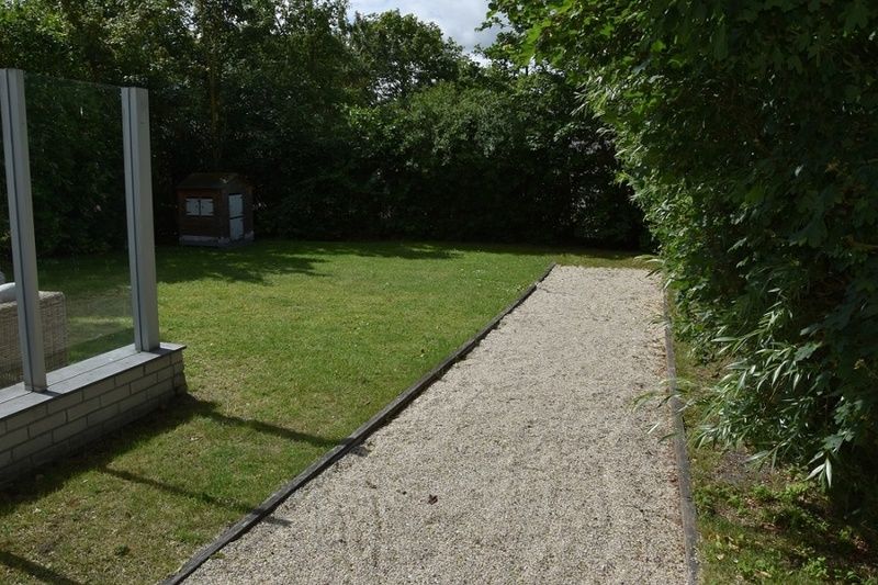 Ontspan in de serene tuin van Vakantiehuis F 455 in De Cocksdorp, Texel, Waddeneilanden, met groen uitzicht en een charmant terras.