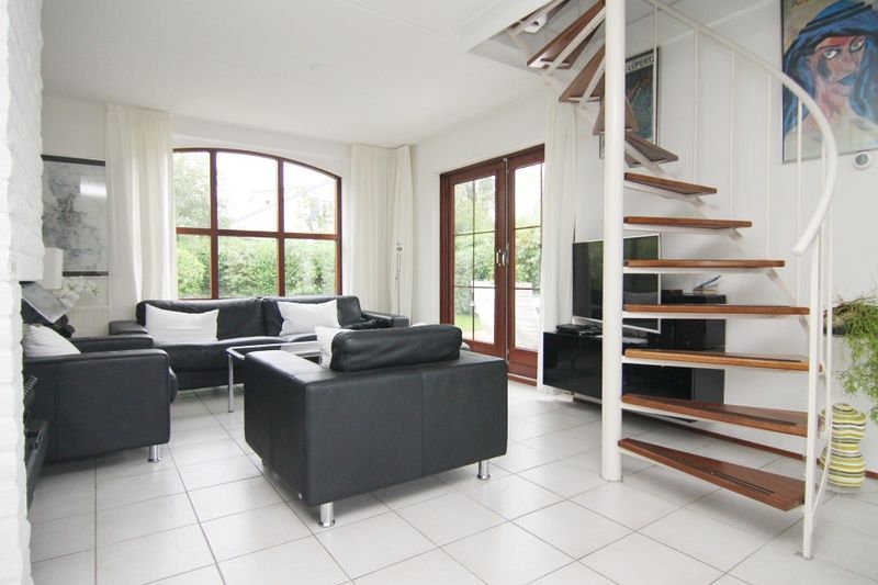 Moderne woonkamer van Vakantiehuis E 638 in De Cocksdorp, Texel, met stijlvolle inrichting en uitzicht op de groene omgeving.