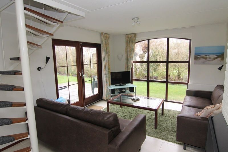 Gezellige woonkamer van Vakantiehuis E 571 in De Cocksdorp, Texel, met uitzicht op de tuin en comfortabele zithoek.