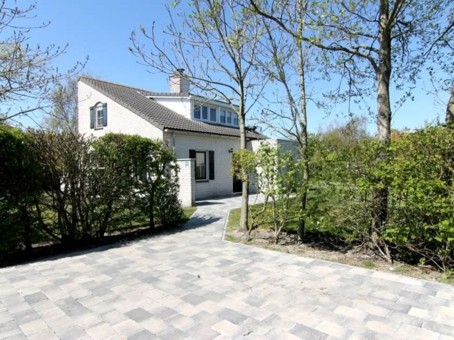 Vakantiehuis F 604 in De Cocksdorp, Texel, biedt een serene buitenomgeving met een betegeld pad en groene natuur rondom.