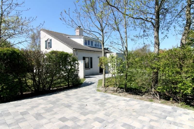 Vakantiehuis F 604 in De Cocksdorp, Texel biedt een serene buitenomgeving met een uitnodigend terras omringd door groen.