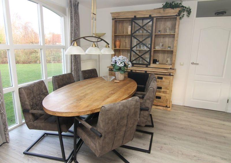 Gezellige eetkamer in Vakantiehuis F 604, De Cocksdorp, Texel, met houten tafel en ruime stoelen, ideaal voor familiebijeenkomsten.