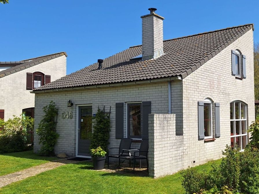 Vakantiehuis E 646 in De Cocksdorp, Texel biedt een charmante buitenruimte met groene tuin en comfortabele zitplek, ideaal voor ontspanning.