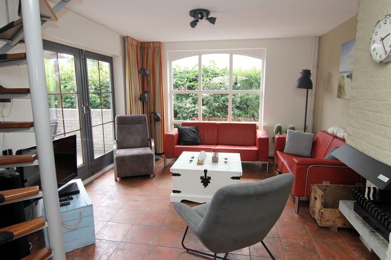 Gezellige woonkamer van Vakantiehuis E 646 in De Cocksdorp, Texel, met comfortabele zitruimte en uitzicht op de groene tuin.