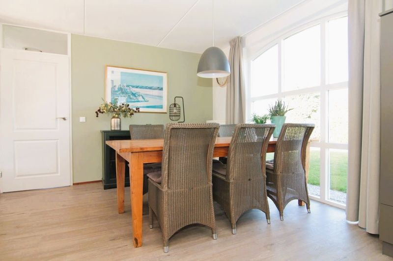 Cozy dining area in Holiday Home F 681, De Cocksdorp, Texel overlooking the garden through large windows.