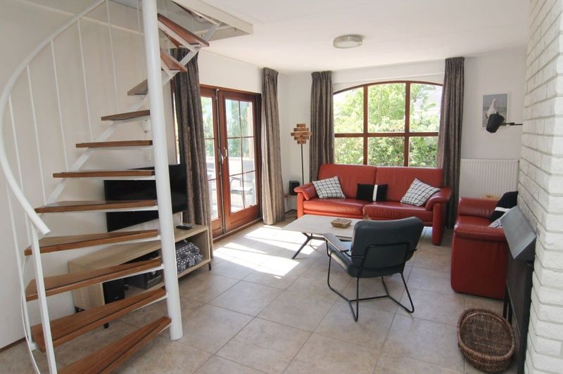 Gezellige woonkamer van Vakantiehuis E 413 in De Cocksdorp, Texel, met ruime zithoek en uitzicht op de groene omgeving.