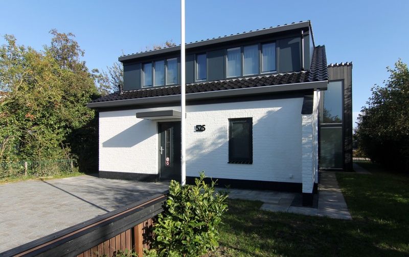 Vacation home E 525 in De Cocksdorp, Texel, offers a modern exterior with spacious garden, ideal for a relaxing stay on the Wadden Islands.