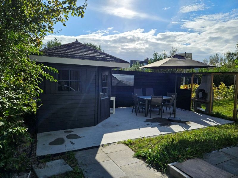 Enjoy the sun on the terrace of Holiday home E 525 in De Cocksdorp, Texel, with comfortable seating and green surroundings.