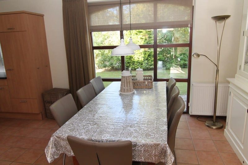 Gemuetliches Esszimmer im Ferienhaus F 713, De Cocksdorp, Texel mit Blick auf den gruenen Garten, ideal fuer einen entspannten Aufenthalt auf den Watteninseln.