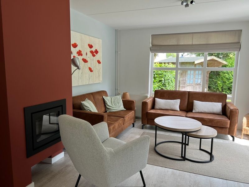 Gezellige woonkamer in Vakantiehuis F 765, De Cocksdorp, Texel met comfortabele zitbanken en uitzicht op de groene tuin.