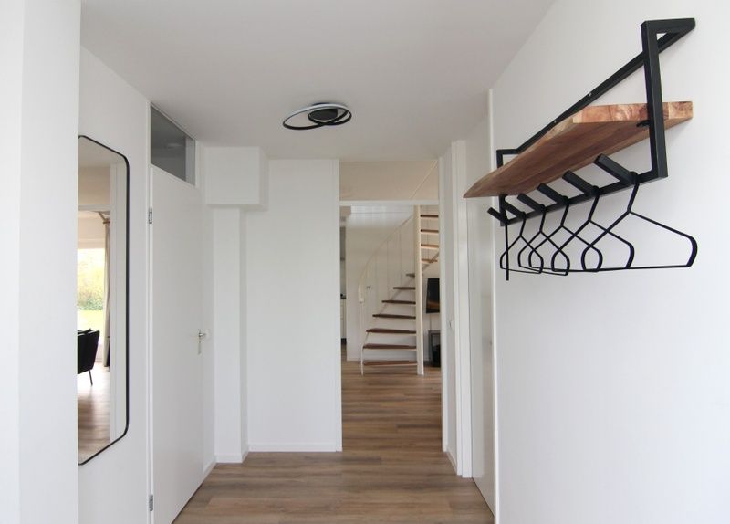 Ingang van Vakantiehuis E 397 in De Cocksdorp, Texel met moderne hal en stijlvolle kapstok, ideaal voor een ontspannen verblijf op de Waddeneilanden.