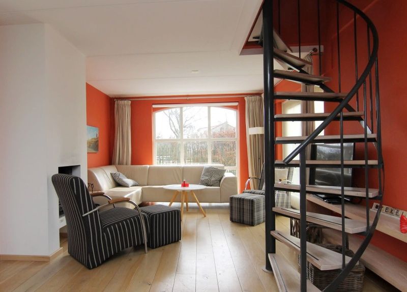Gezellige woonkamer van Vakantiehuis E 634 in De Cocksdorp, Texel, met een moderne wenteltrap en comfortabele zithoek.