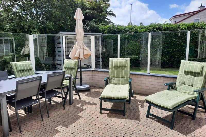 Geniet van het zonnige terras bij Vakantiehuis E 409 in De Cocksdorp, Texel, met comfortabele ligstoelen en een ruime eettafel.