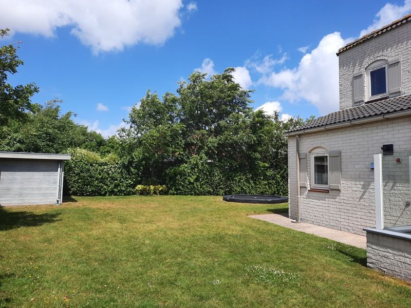Ruime tuin van Vakantiehuis E 409 in De Cocksdorp, Texel, omgeven door groene natuur voor een ontspannen verblijf op de Waddeneilanden.