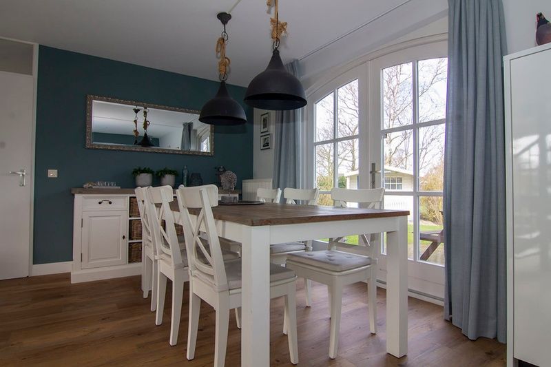 Gezellige eetkamer in Vakantiehuis F 602, De Cocksdorp, Texel, met houten tafel, witte stoelen en uitzicht op de groene tuin.