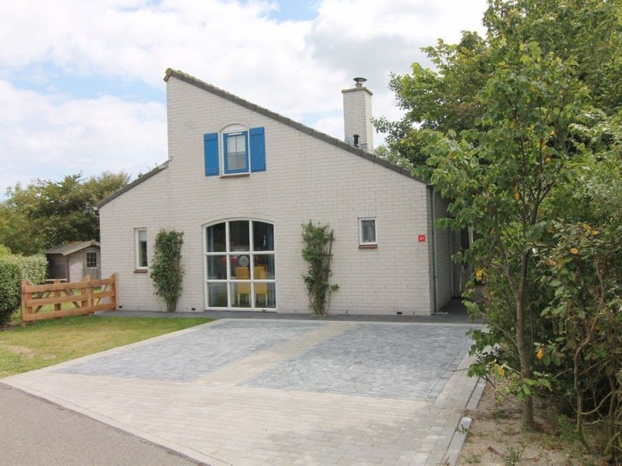 Vakantiehuis E 421 in De Cocksdorp, Texel, biedt een uitnodigende entree met een ruime oprit en groene omgeving op de Waddeneilanden.