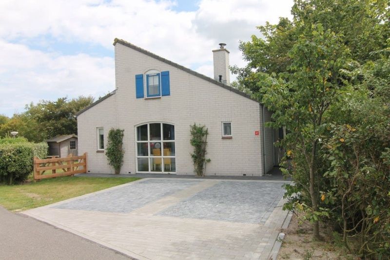 Vakantiehuis E 421 in De Cocksdorp, Texel, biedt een charmante verblijfservaring met een uitnodigende voorgevel en groene omgeving.