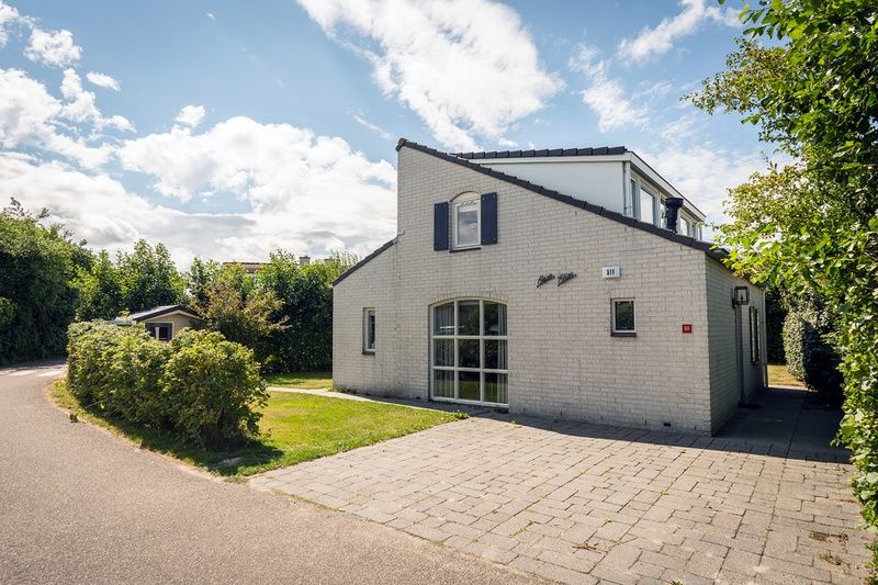 Das Ferienhaus E 511 in De Cocksdorp auf Texel bietet einen schoenen Aussenbereich mit gruener Umgebung und einer einladenden Terrasse.