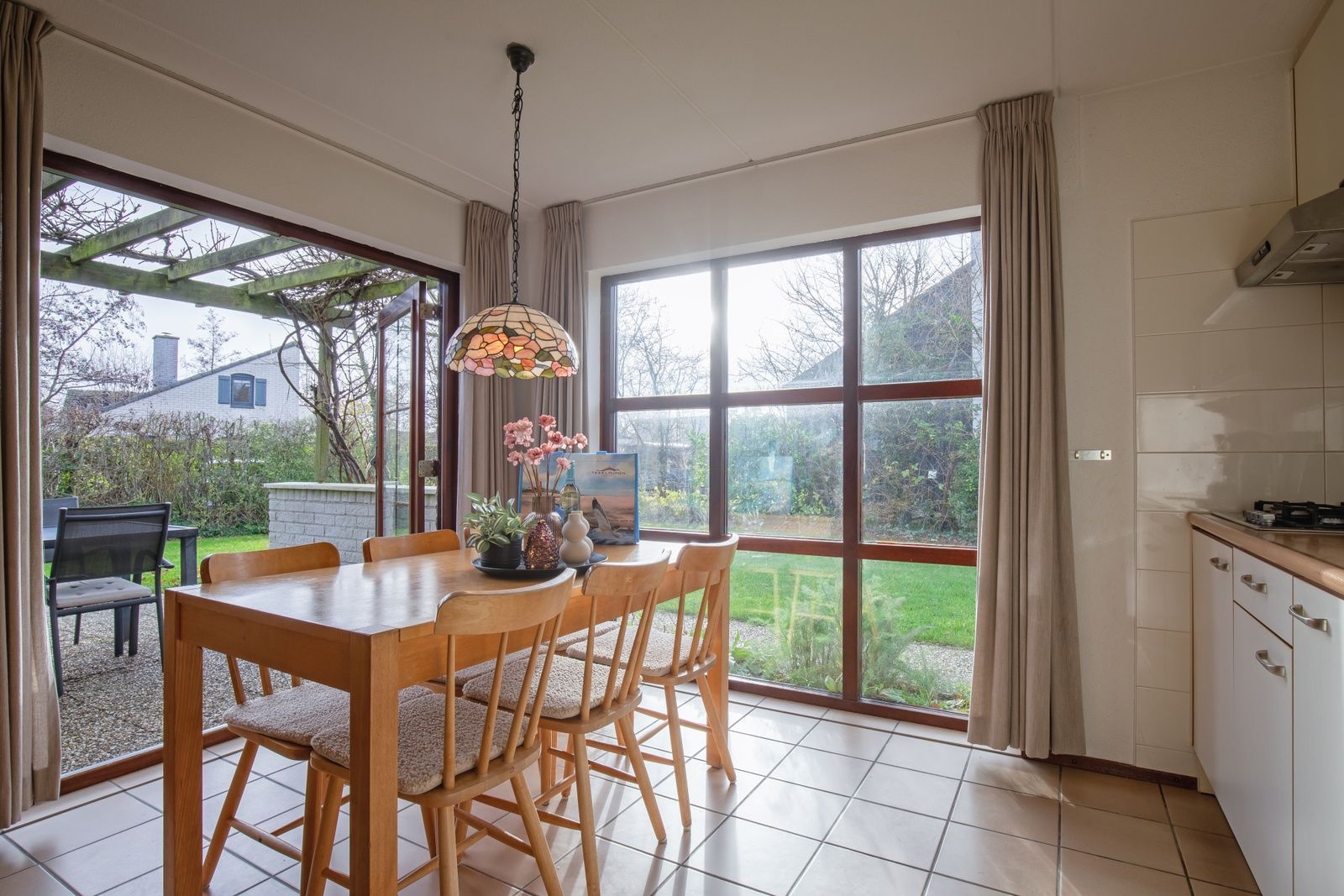 Gezellige eetruimte in vakantiehuis Annemein, De Cocksdorp, Texel, met uitzicht op de tuin en veel natuurlijk licht.