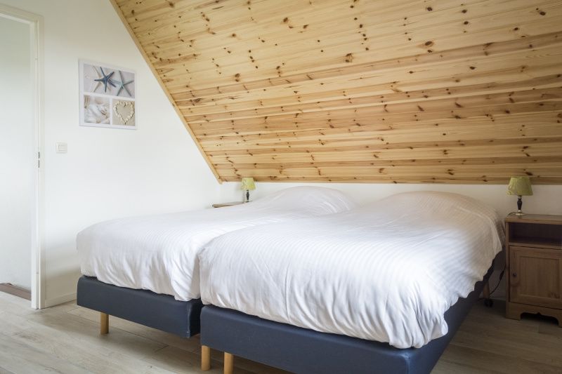 Sfeervolle slaapkamer met houten afwerking in Bungalow Klein Axel, De Cocksdorp, Texel, voor een goede nachtrust.