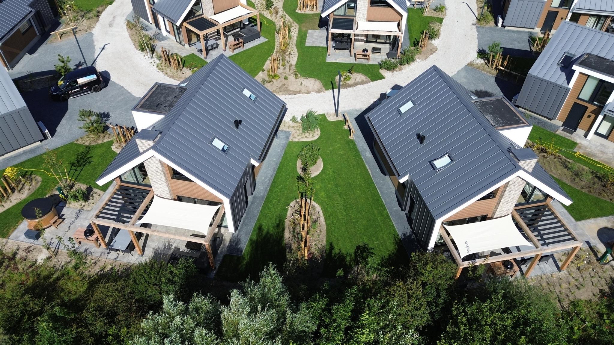 Luchtfoto van Duinvilla Wellness 4, een luxe vakantiehuis in De Cocksdorp, Texel, omgeven door groene natuur en moderne architectuur.