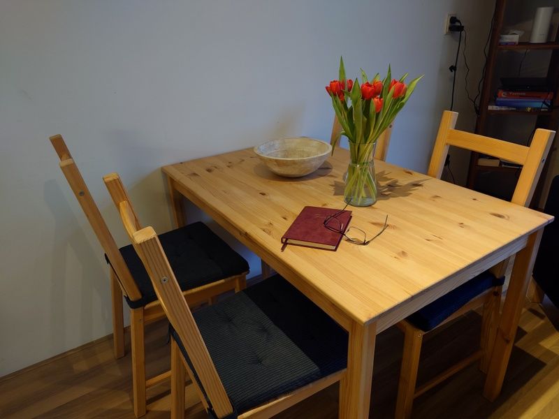 Esstisch im Ferienhaus Kikkerpoel, De Cocksdorp, Texel mit Tulpen und Notizbuch, ideal fuer entspannte Mahlzeiten.