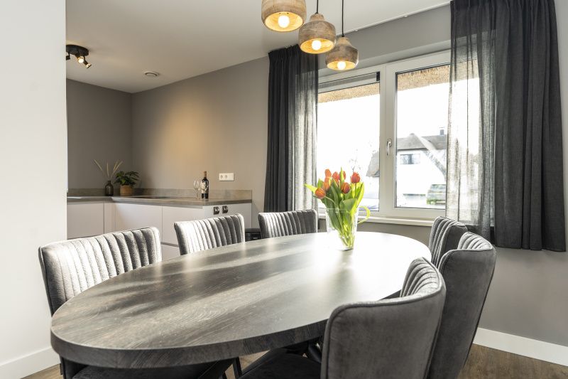 Eetgedeelte in Duinoord Texel vakantiehuis, De Cocksdorp, met grote tafel en bloemen op tafel.
