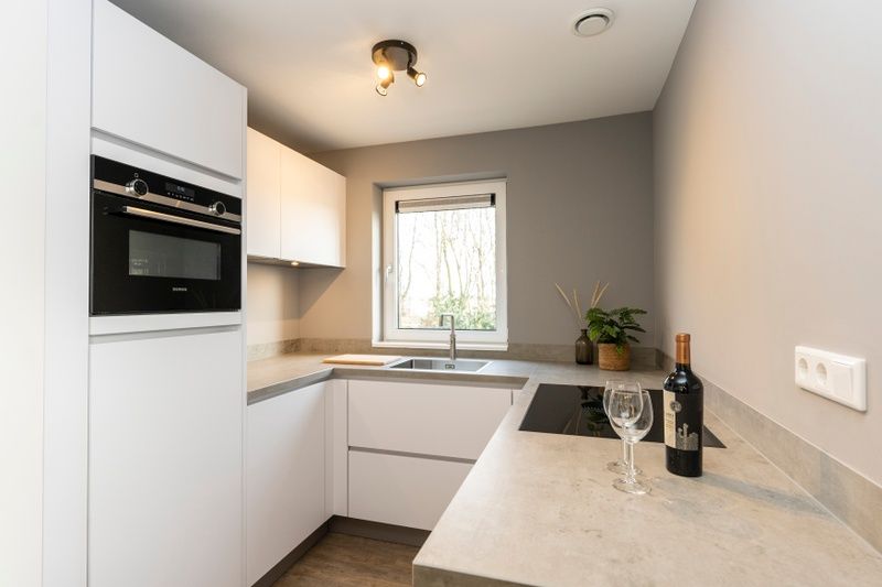 Compacte en moderne keuken in Duinoord Texel vakantiehuis, De Cocksdorp, met uitzicht op tuin.