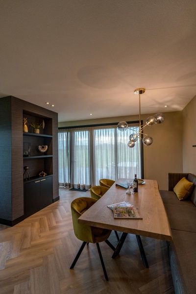 Ruime eetkamer in 6 persoons vakantiewoning, De Cocksdorp, Texel met houten tafel en moderne verlichting.