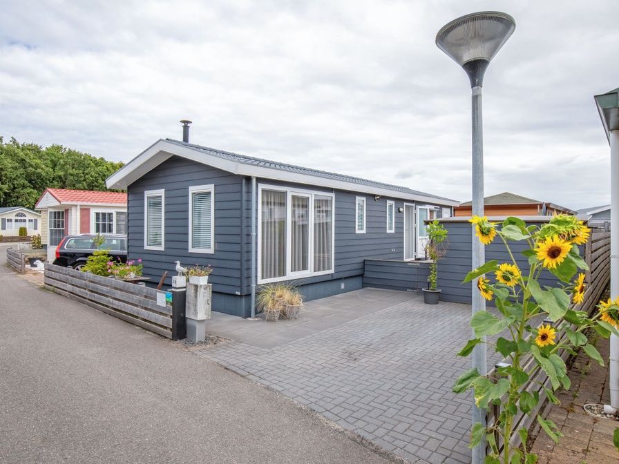 Chalet Bregkoog 52 in De Koog, Texel, met zonnige veranda en kleurrijke zonnebloemen bij Chaletpark Bregkoog.