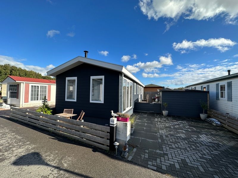Chalet Bregkoog 52 in De Koog, Texel, met omheinde tuin en blauwe lucht bij Chaletpark Bregkoog.