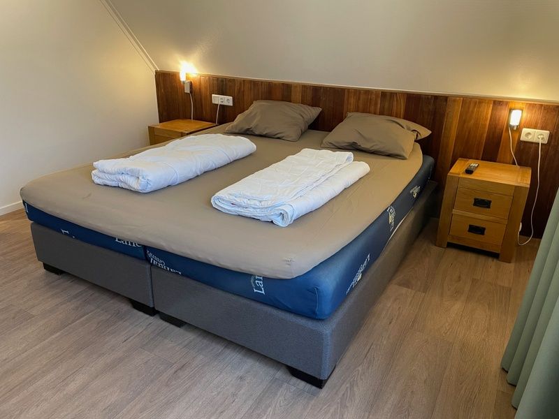 Gezellige slaapkamer in vakantiehuis Vogelmient 55, De Koog, Texel met comfortabel tweepersoonsbed en warme houten accenten.